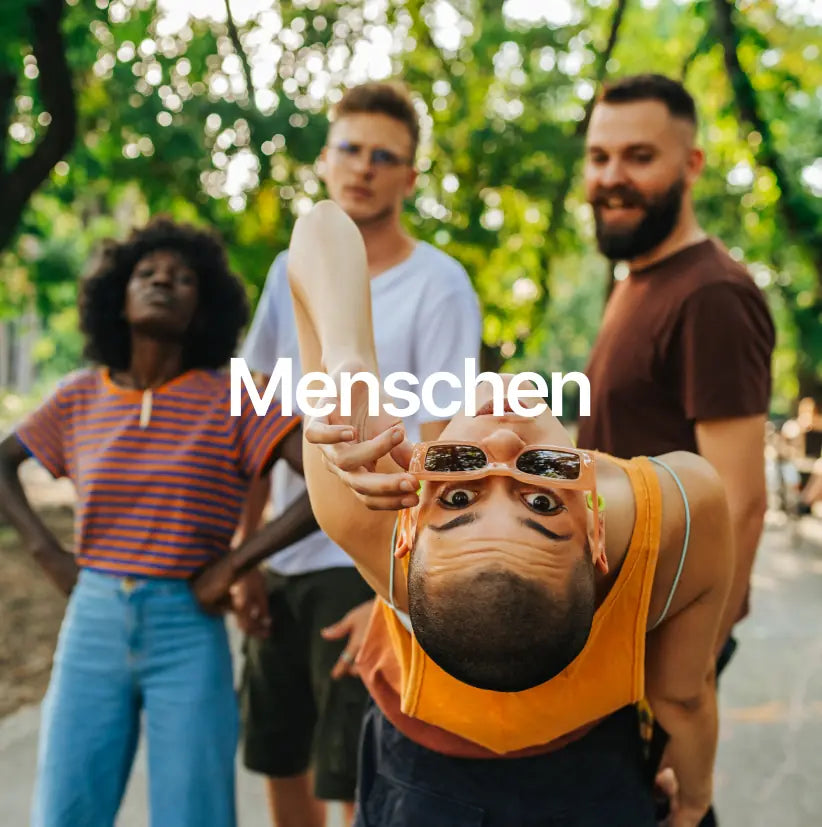 Gruppe von vier Personen im Park, die miteinander lachen und Spaß haben, symbolisiert die Gemeinschaft und Zusammenarbeit bei stonearts®.